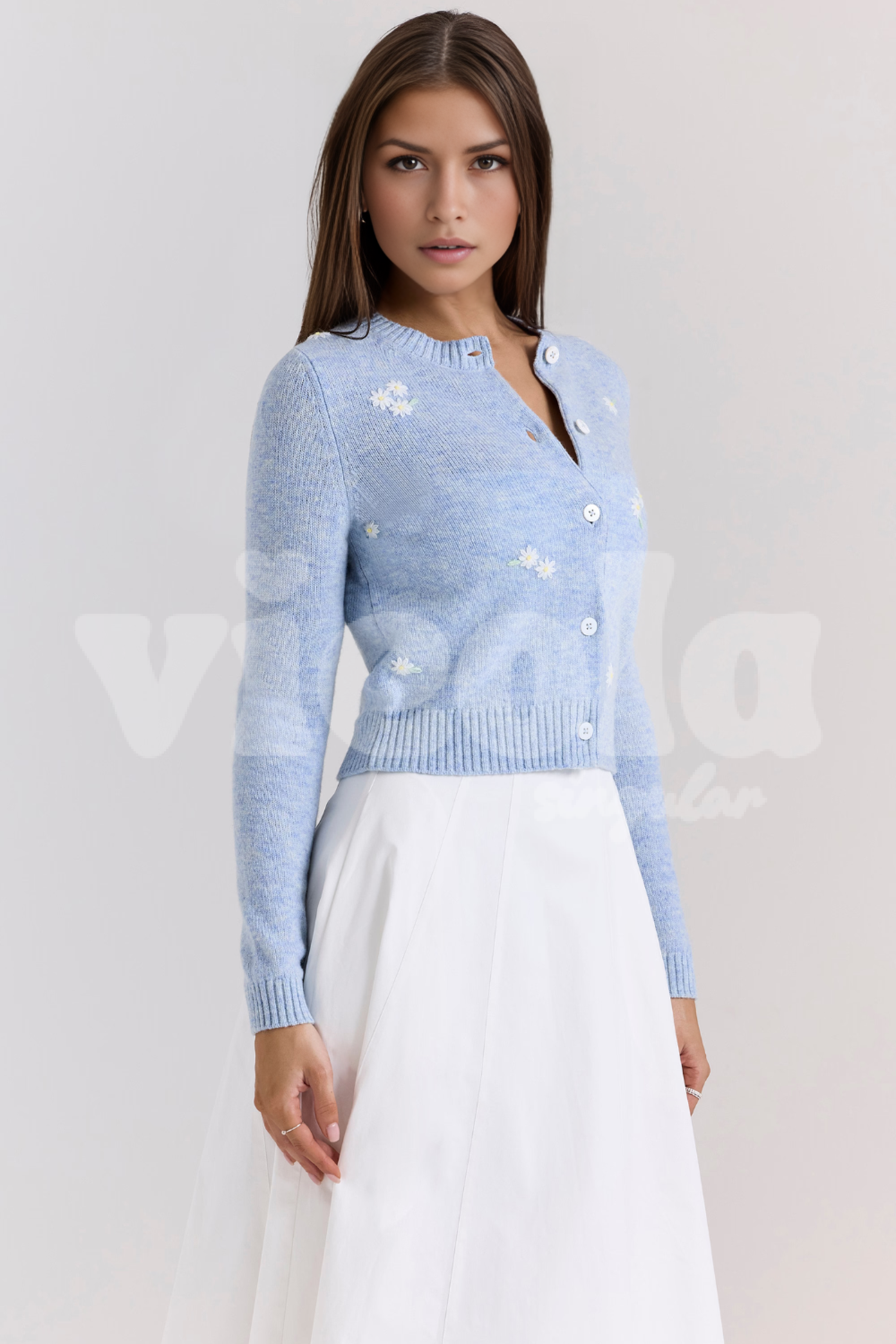 Woman wearing a light blue sweater with floral patterns on a plain background