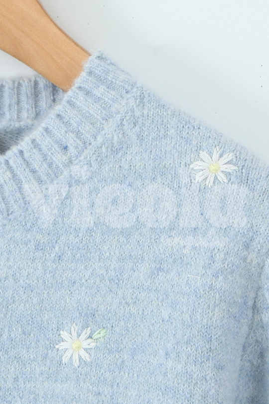 Light blue sweater with white daisy patterns on a plain background